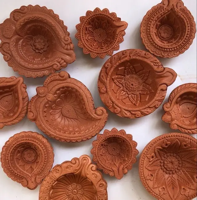 Unglazed terracotta diyas arranged in a tray after pressing
